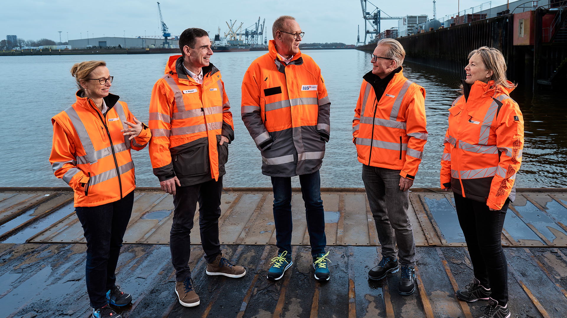 Die Mitglieder des Vorstands in orangen Schutzjacken am Hafen (Foto)