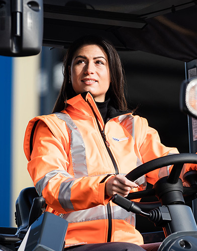 A woman with brown hair is driving a forklift (Photo)