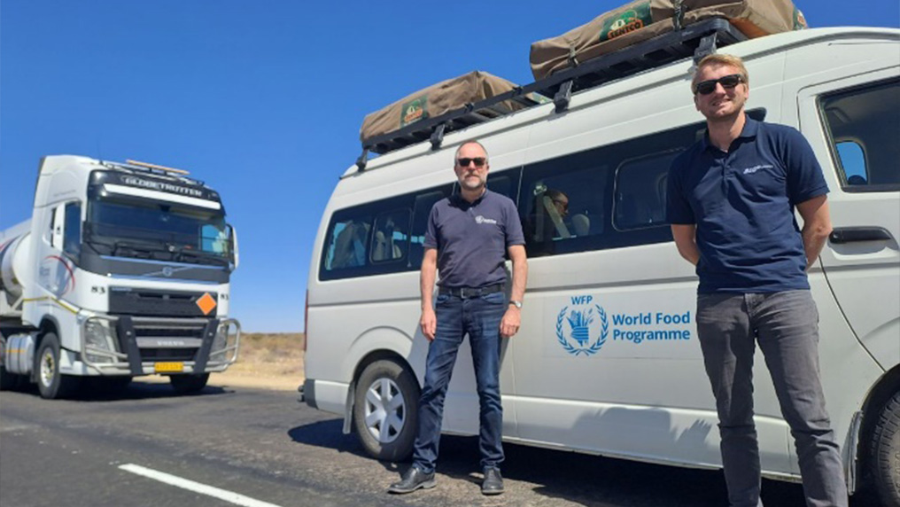 Two men in front of a car of the UN World Food Programme (Photo)