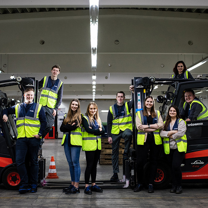 Young BLG employees pose next to two forklift trucks (Photo)