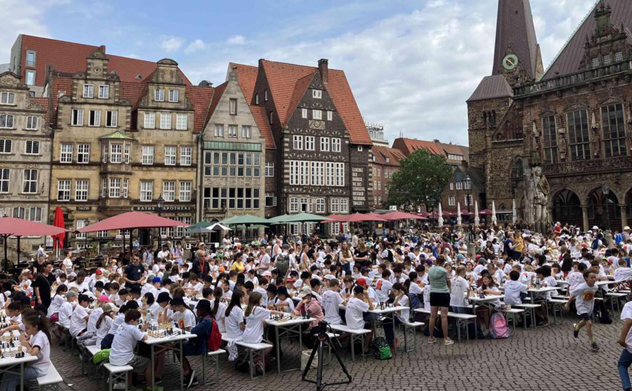 A photo of Bremen's market square with lots of children playing chess there (Photo)