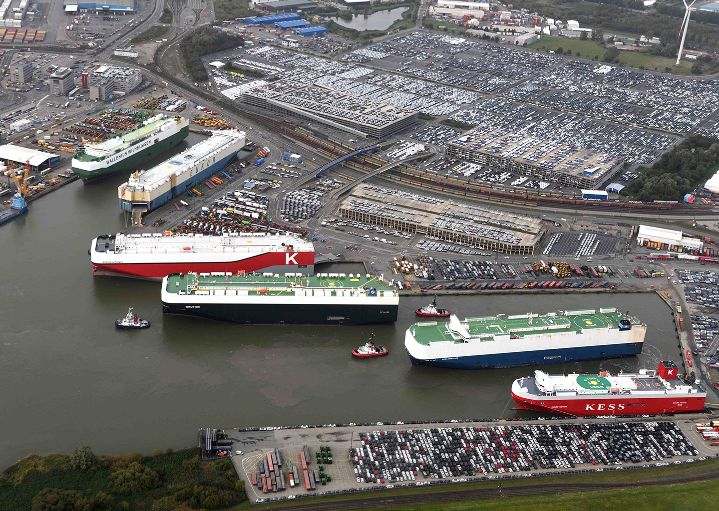 A view of the harbor with many parked cars and large container ships (Photo)