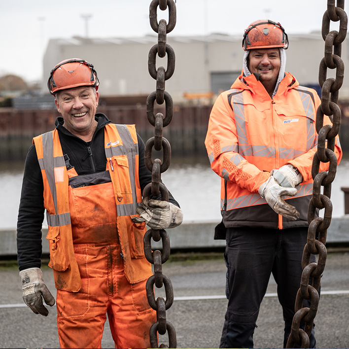 Two smiling men in orange protective suits (Photo)