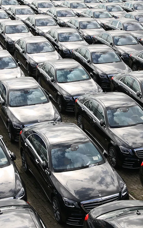 Luftaufnahme mehrerer langer, dicht aneinander geparkter Reihen schwarzer Autos