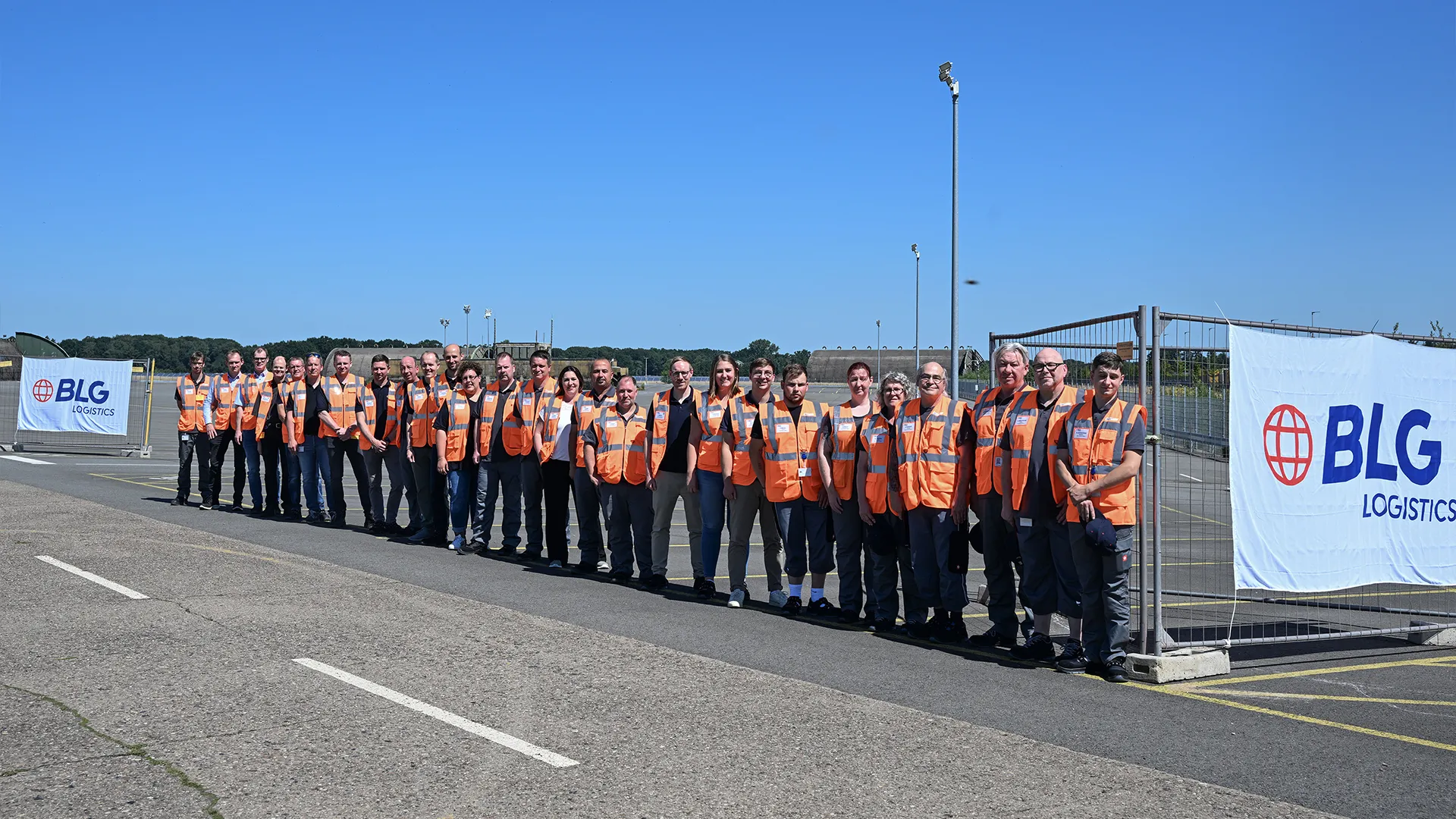Gruppenfoto von Mitarbeiter draußen in orangen Westen (Foto)