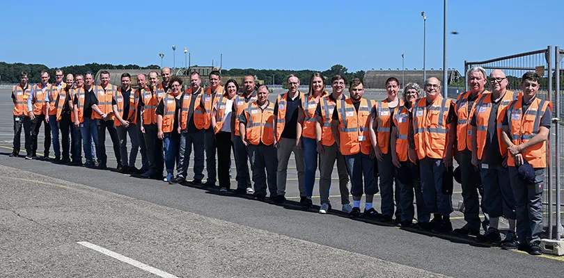 Gruppenfoto von Mitarbeiter draußen in orangen Westen Preview (Foto)