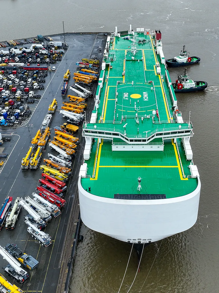 Lauftaufnahme von Boot mit Landestation am Hafen und vielen Fahrezeugen daneben geparkt (Foto)