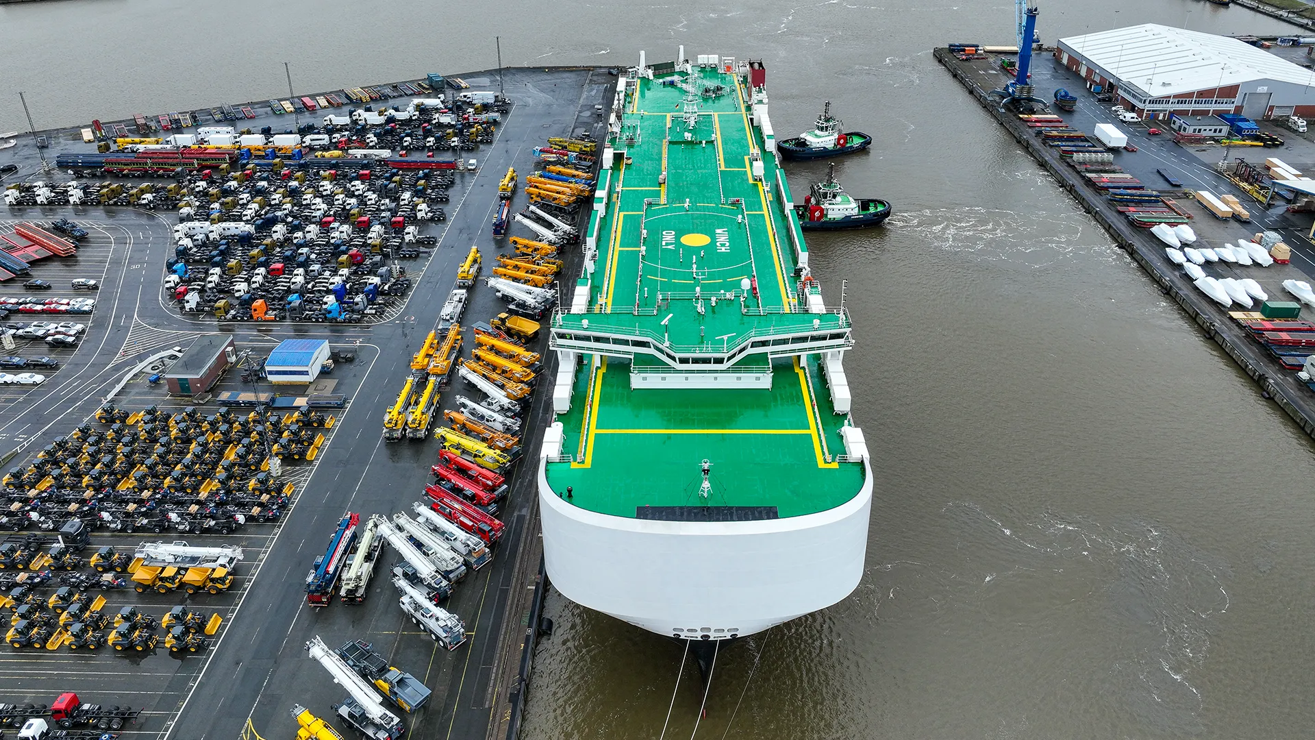 Lauftaufnahme von Boot mit Landestation am Hafen und vielen Fahrezeugen daneben geparkt (Foto)