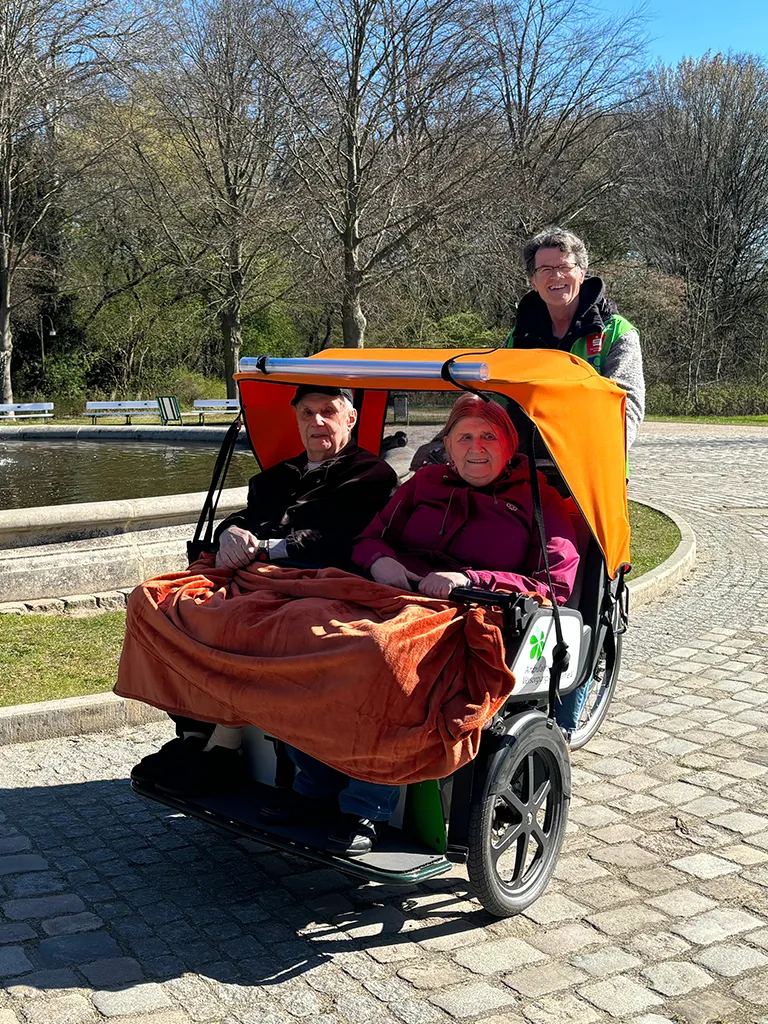 Senioren Paar in Transportfahrzeug blicken fröhlich in die Kamera (Foto)