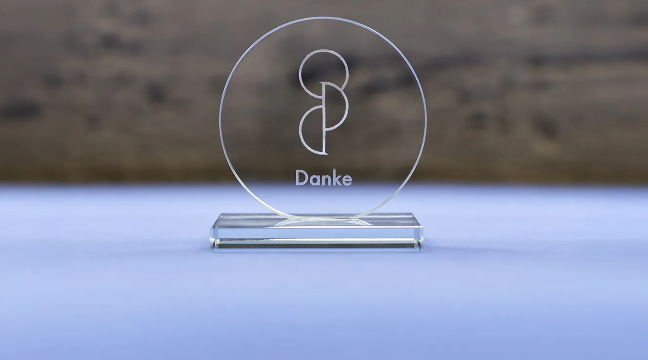 Pokal mit "Danke" Aufschrift auf blauem Tisch (Foto)