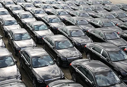 Aerial view of multiple long rows of closely parked black cars 