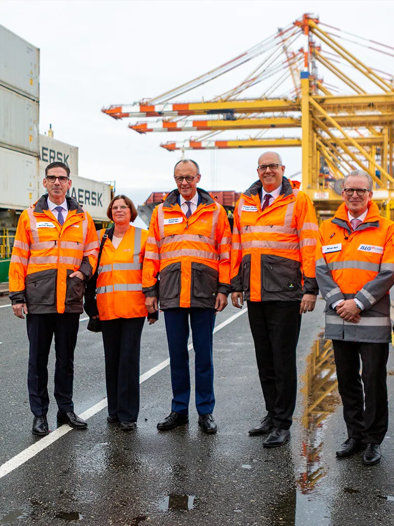 Board members and Friedrich Merz at the harbor wearing orange vests (Photo)