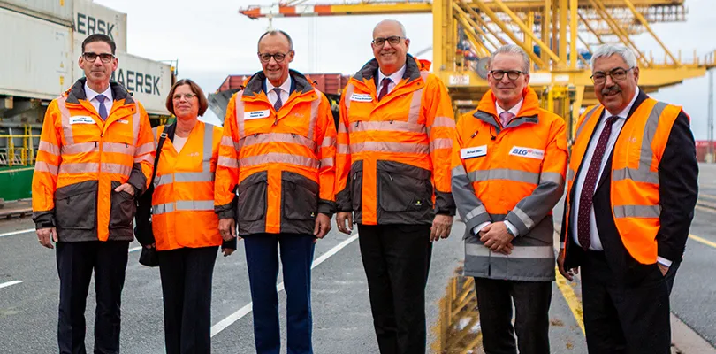 Board members and Friedrich Merz at the harbor wearing orange vests (Photo)