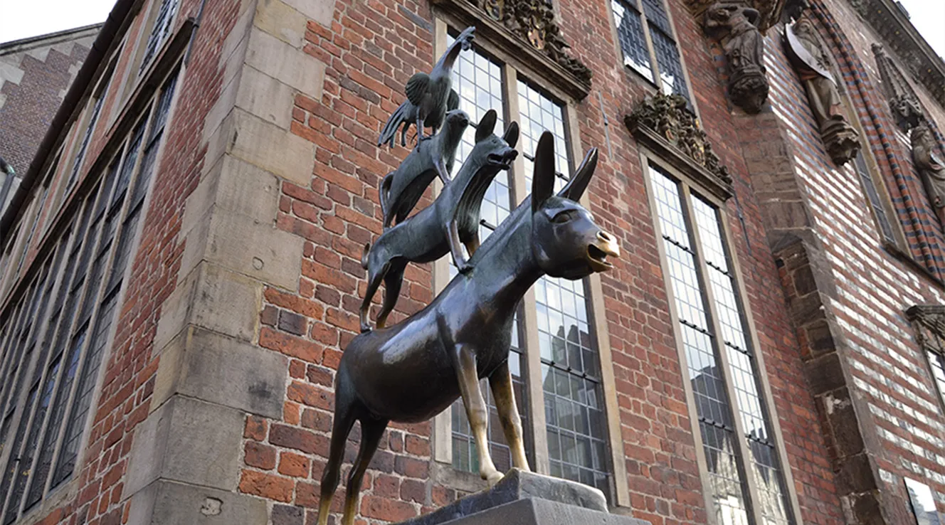 Bremen Town Musicians statue in front of a brick facade (Photo)